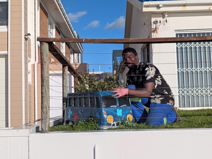 Franco smiling while working on a colourful garden planter